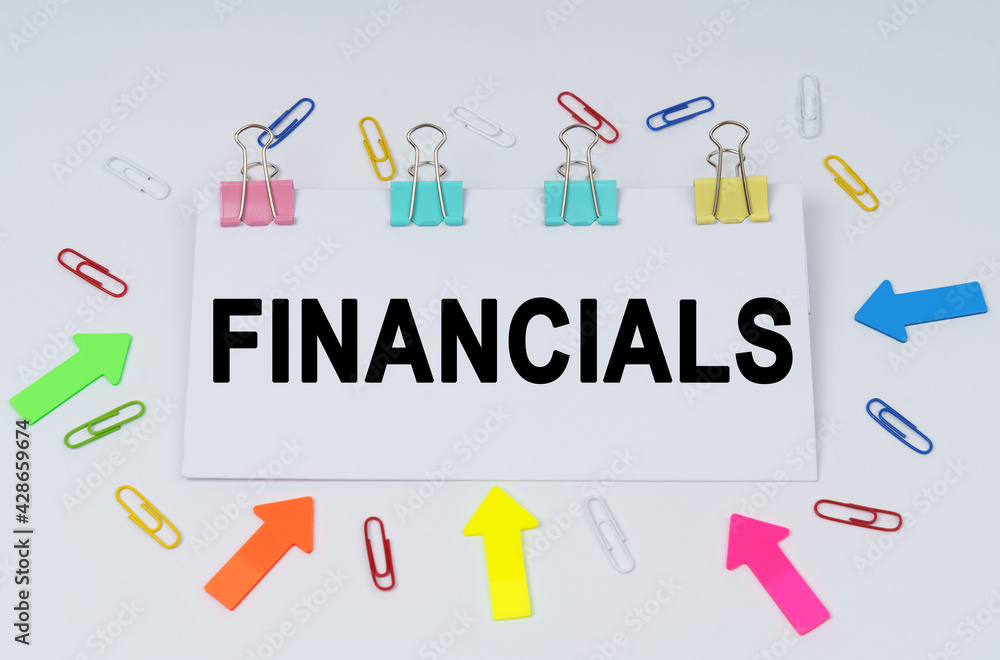 On the table there are paper clips and directional arrows, a sign that says - FINANCIALS On the table there are paper clips and directional arrows, a sign that says - FINANCIALS
