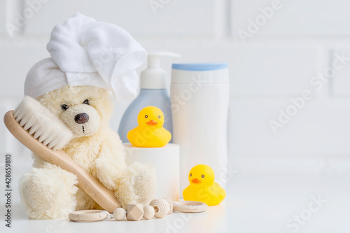 Obraz na plátně Baby bath accessories, baby care, a yellow bear with a towel on its head, a brush and bottles of shampoo