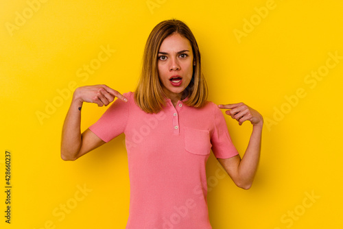 Young caucasian skinny woman isolated on yellow background points down with fingers, positive feeling.