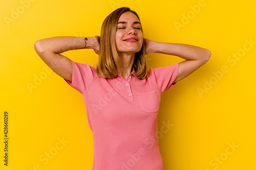 Young caucasian skinny woman isolated on yellow background feeling confident, with hands behind the head.
