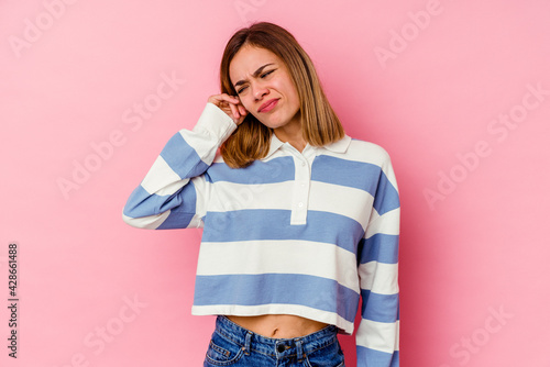 Young caucasian woman isolated on pink background covering ears with fingers, stressed and desperate by a loudly ambient.