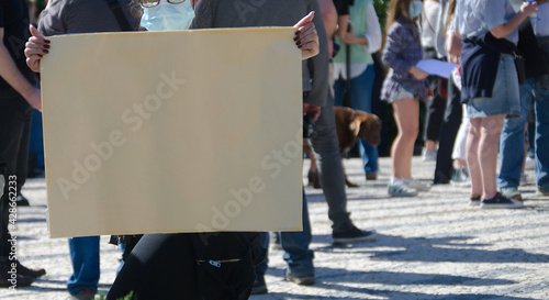 Mulher no meio de uma multidão de uma manifestação a segurar um cartaz, em tempo de pandemia de COVID-19, sinal de protesto photo