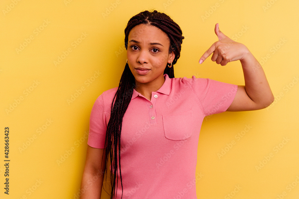 Young african american woman isolated on yellow background person pointing by hand to a shirt copy space, proud and confident Young african american woman isolated on yellow background person pointing by hand to a shirt copy space, proud and confident
