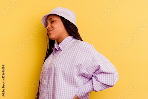 Young african american woman isolated on yellow background suffering a back pain.