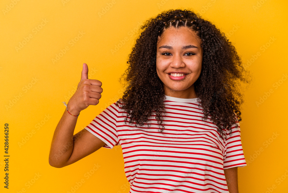 Young african american woman isolated on yellow background smiling and raising thumb up Young african american woman isolated on yellow background smiling and raising thumb up