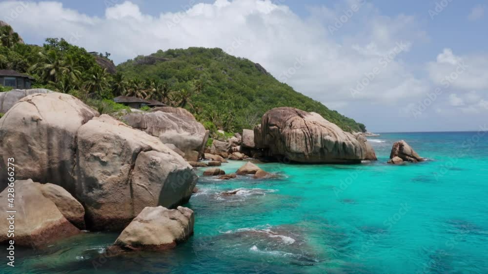 Aerial pan of Seychelles, Africa, beach coastline granite rock formations with private bungalows and turquoise blue ocean water. Drone shot of La Digue island travel destination. Exotic paradise. Aerial pan of Seychelles, Africa, beach coastline granite rock formations with private bungalows and turquoise blue ocean water. Drone shot of La Digue island travel destination. Exotic paradise.