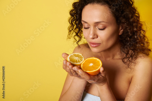 Beauty portrait of attractive curly half-naked woman enjoying citrus scent in her hands