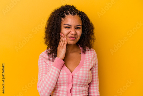 Young african american woman isolated on yellow background having a strong teeth pain, molar ache.