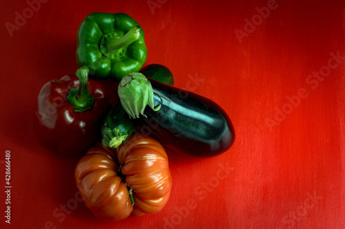 Six gros légumes de saison colorés,  disposés sur un fond rouge, vue en plongée © Olivier Tabary