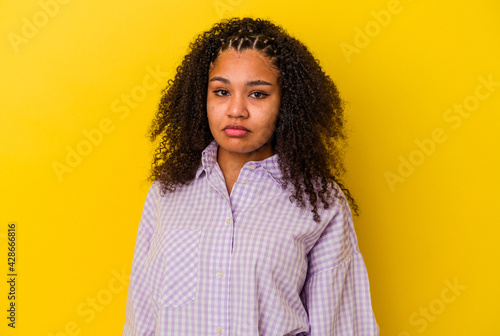 Young african american woman isolated on yellow background sad, serious face, feeling miserable and displeased.