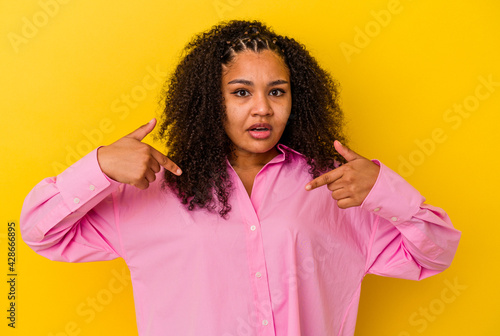 Young african american woman isolated on yellow background points down with fingers, positive feeling.