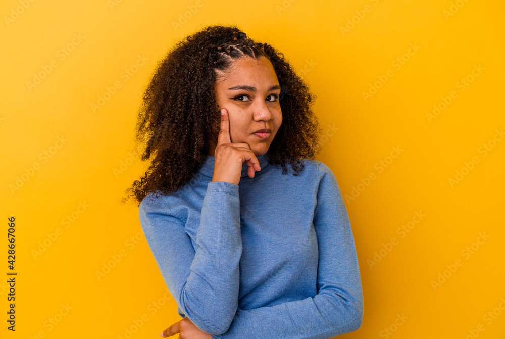 Young african american woman isolated on yellow background contemplating, planning a strategy, thinking about the way of a business. Young african american woman isolated on yellow background contemplating, planning a strategy, thinking about the way of a business.