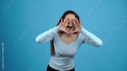 The frightened young brunette puts her hands around her mouth, terrified and screaming for help. Asian with dark hair, dressed in a blue blouse, isolated on a dark blue background in the studio. The