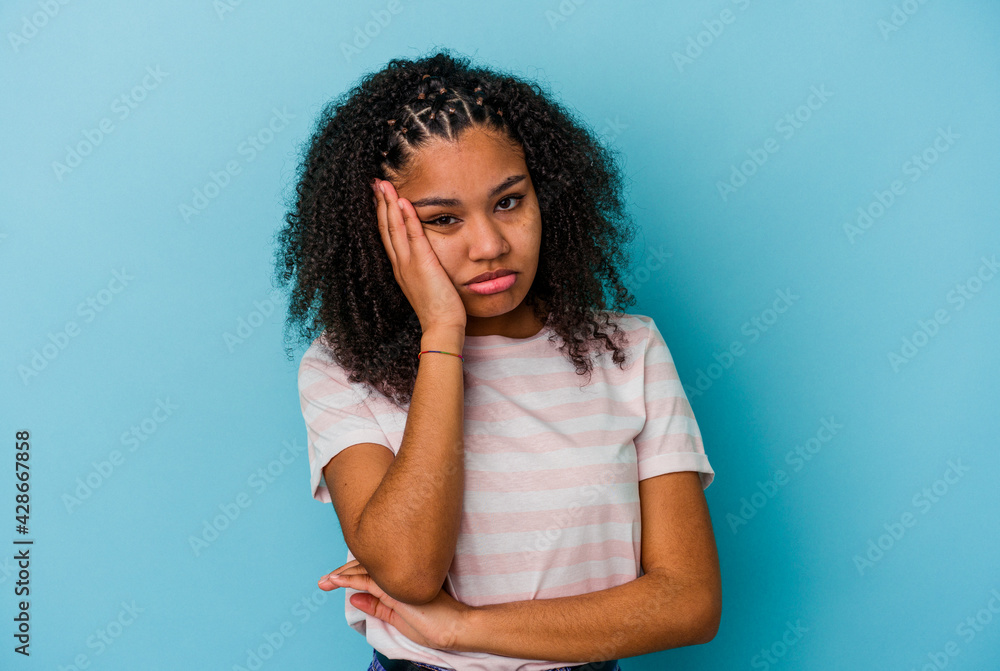 Young african american woman isolated on blue background who is bored, fatigued and need a relax day. Young african american woman isolated on blue background who is bored, fatigued and need a relax day.