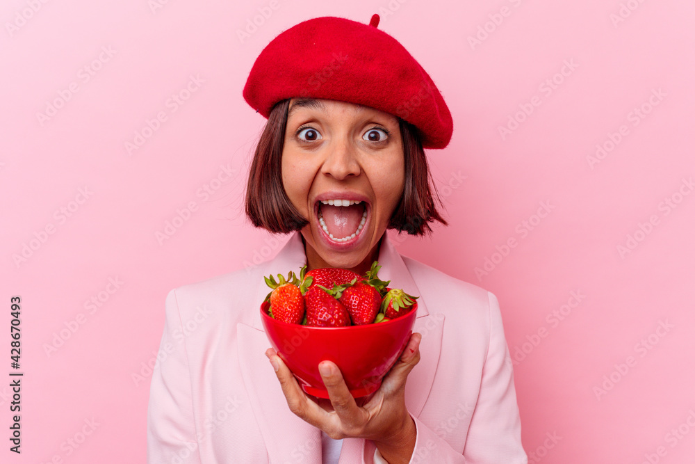 Young mixed race woman eating strawberry isolated on pink background Young mixed race woman eating strawberry isolated on pink background