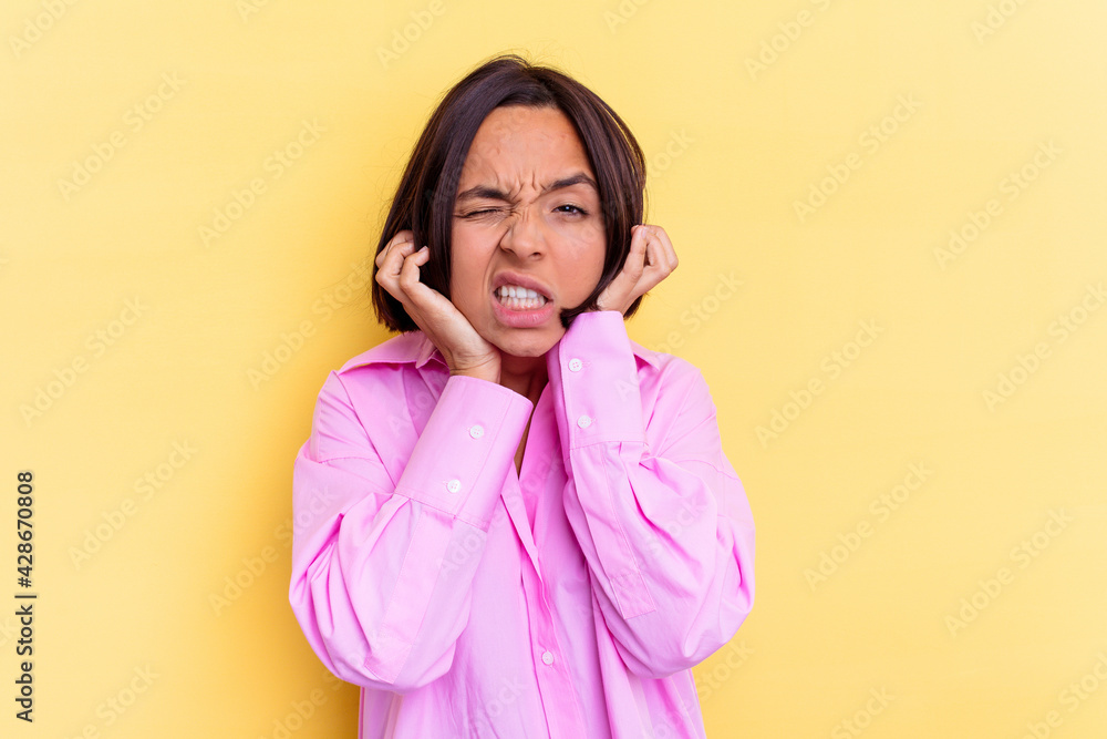 Young mixed race woman isolated on yellow background covering ears with hands. Young mixed race woman isolated on yellow background covering ears with hands.