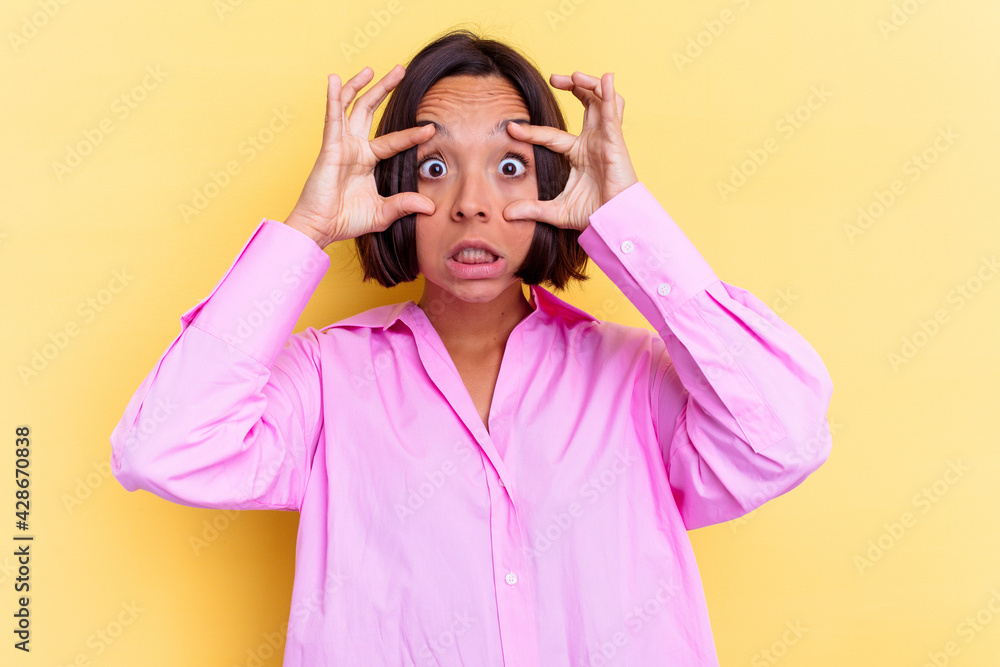 Young mixed race woman isolated on yellow background keeping eyes opened to find a success opportunity. Young mixed race woman isolated on yellow background keeping eyes opened to find a success opportunity.