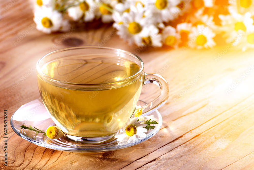 Cup of hot herbal tea with chamomile flowers on a wooden table Cup of hot herbal tea with chamomile flowers on a wooden table