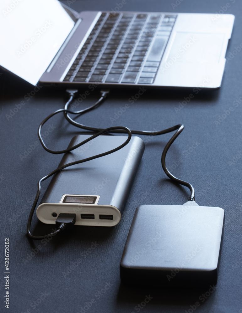 External peripheral gadgets: the power bank and hard drive are connected to  a laptop or ultrabook. Charging and data transfer. Dark table Stock-Foto |  Adobe Stock