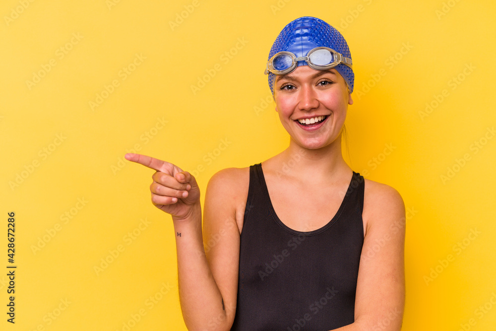 Young swimmer venezuelan woman isolated on yellow background smiling cheerfully pointing with forefinger away. Young swimmer venezuelan woman isolated on yellow background smiling cheerfully pointing with forefinger away.