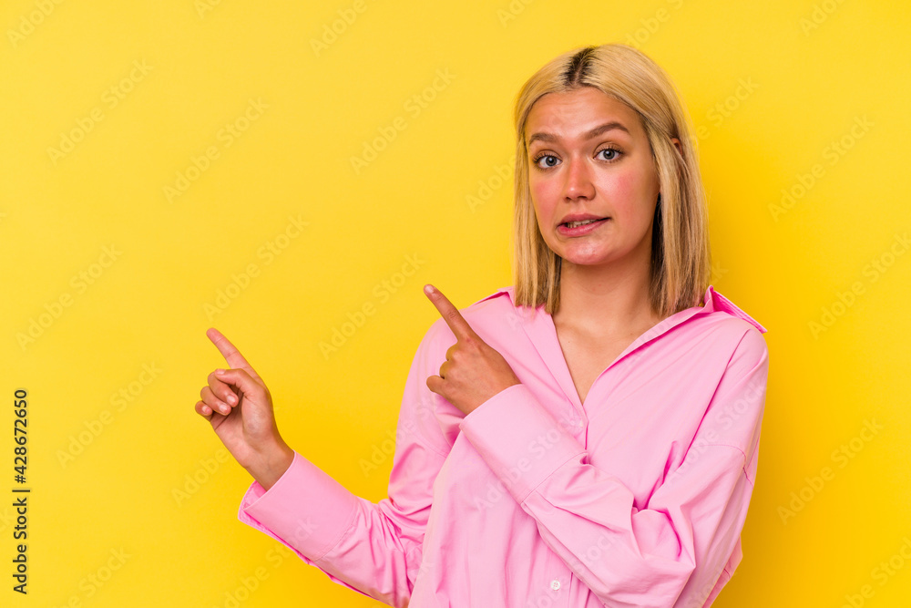 Young venezuelan woman isolated on yellow background shocked pointing with index fingers to a copy space. Young venezuelan woman isolated on yellow background shocked pointing with index fingers to a copy space.