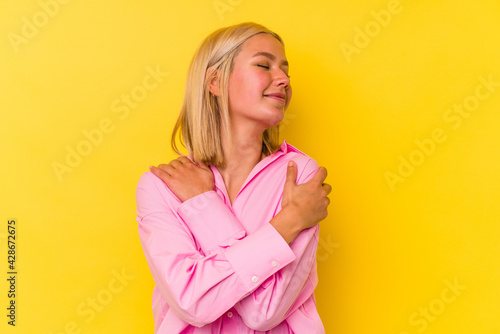 Young venezuelan woman isolated on yellow background hugs  smiling carefree and happy.