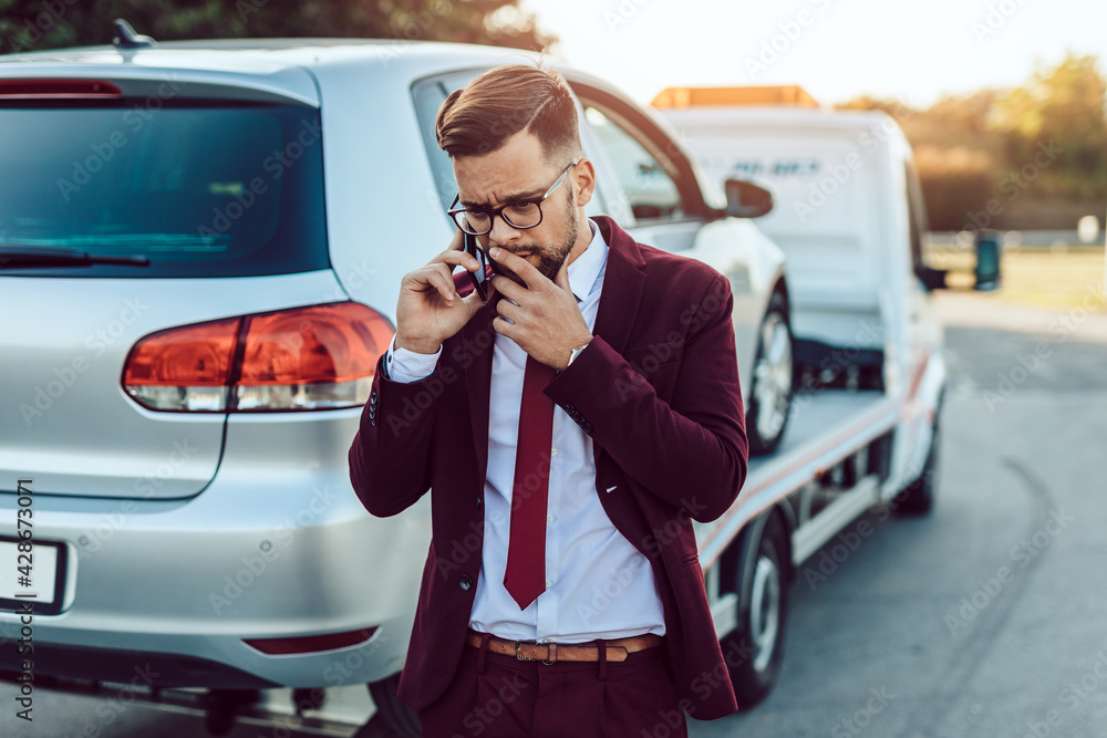 Naklejka premium Elegant middle age business man calling towing service for help on the road. Roadside assistance concept.