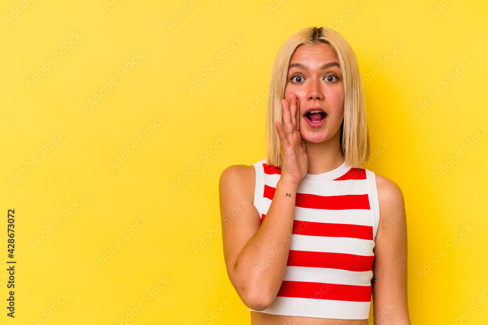 Young venezuelan woman isolated on yellow background shouts loud, keeps eyes opened and hands tense. Young venezuelan woman isolated on yellow background shouts loud, keeps eyes opened and hands tense.