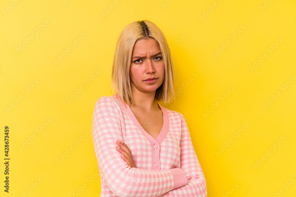 Young venezuelan woman isolated on yellow background frowning face in displeasure, keeps arms folded. Young venezuelan woman isolated on yellow background frowning face in displeasure, keeps arms folded.