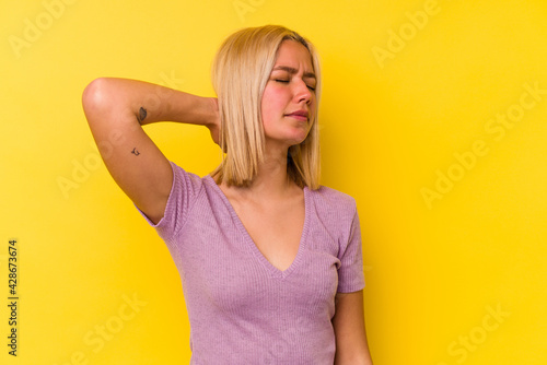 Young venezuelan woman isolated on yellow background having a neck pain due to stress, massaging and touching it with hand.