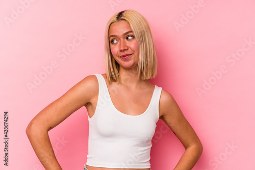 Young venezuelan woman isolated on pink background dreaming of achieving goals and purposes