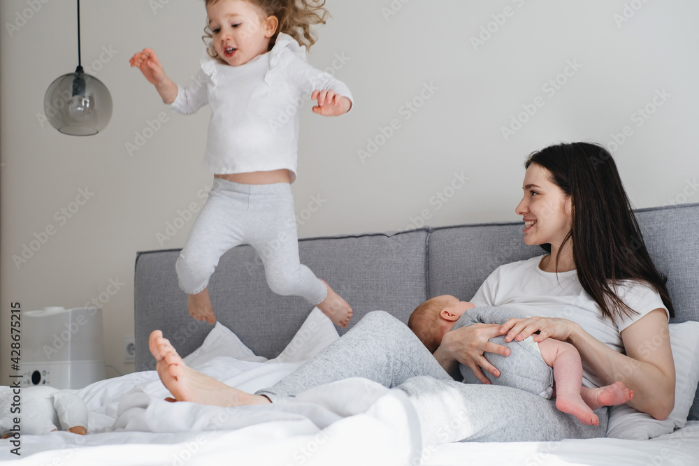 Breast feeding mama with two kids at home. Baby breastfeed on mothers
