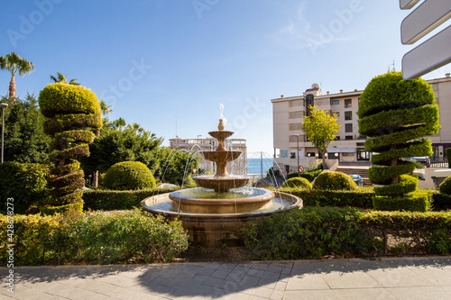Figuredly trimmed lush hedges of juniper and fountain in the cityscape of Villajoyosa Spain. photo