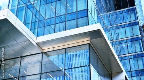 Abstract closeup of the glass-clad facade of a modern building covered in reflective plate glass. Architecture abstract background. Glass wall and facade detail. Velvia graphic filter.