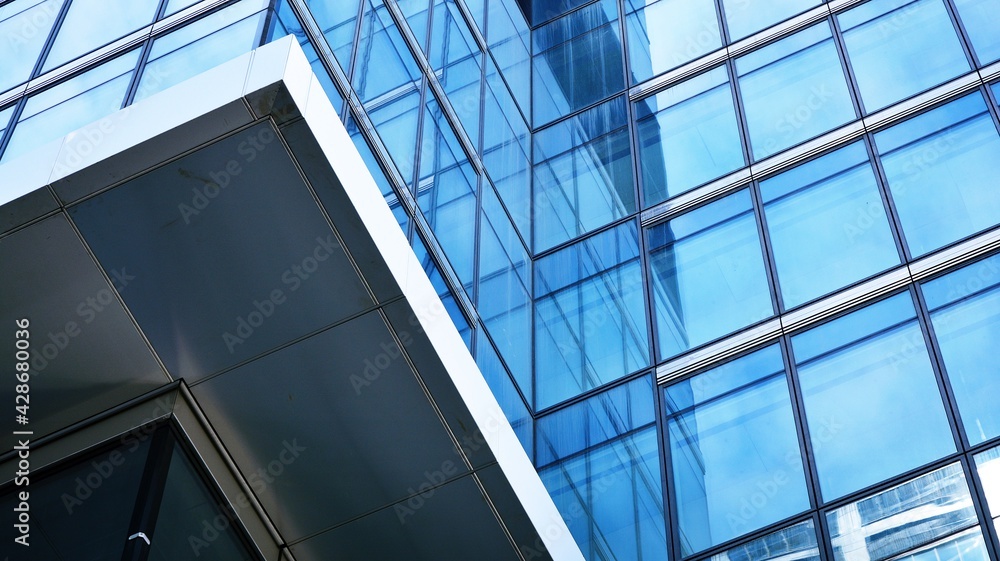Abstract closeup of the glass-clad facade of a modern building covered in reflective plate glass. Architecture abstract background. Glass wall and facade detail. Velvia graphic filter. Abstract closeup of the glass-clad facade of a modern building covered in reflective plate glass. Architecture abstract background. Glass wall and facade detail. Velvia graphic filter.