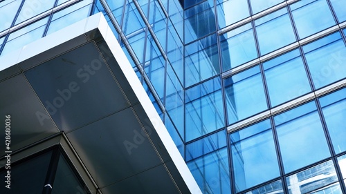 Abstract closeup of the glass-clad facade of a modern building covered in reflective plate glass. Architecture abstract background. Glass wall and facade detail. Velvia graphic filter.