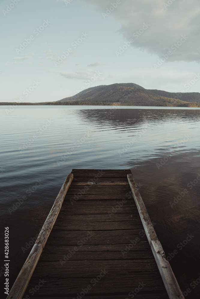 Boardwalk to a still lake with a mountain in the background — The landscape at dusk at Queens Lake, New South Wales