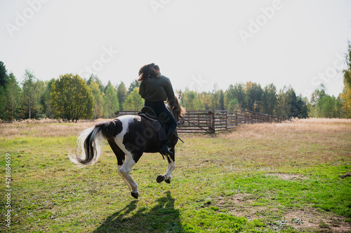 A pretty girl came to the country equestrian club and rides a horse through the fields in the fall © Anna Kosolapova