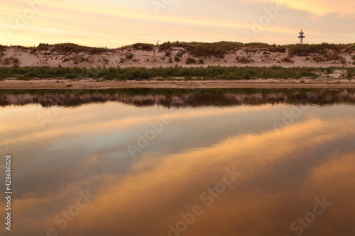 Reflection of sky in front of dunes with lighthouse