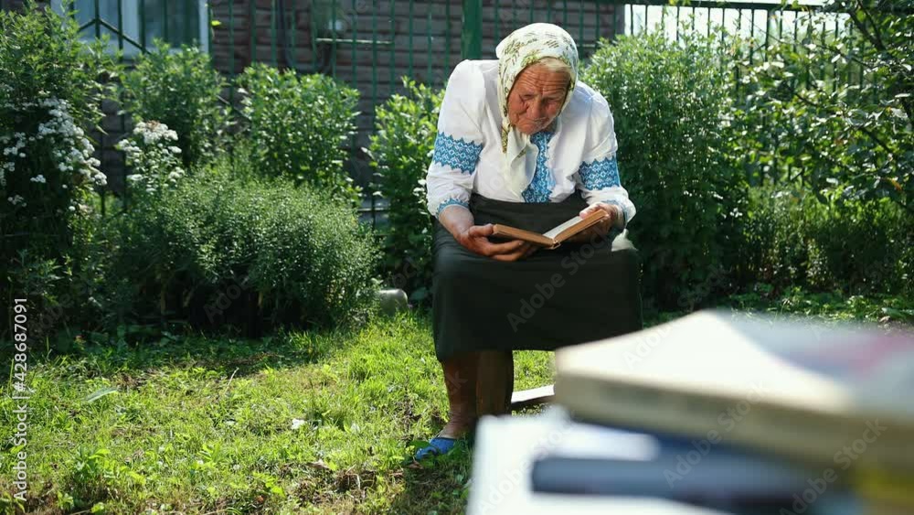 An old grandmother is sitting on the street and reading a book. Vyshyvanka An old grandmother is sitting on the street and reading a book. Vyshyvanka
