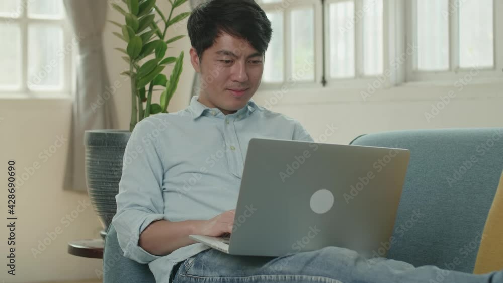 Asian Male Use Laptop Computer And Smiling In Living Room While Lying On Sofa
Asian Male Use Laptop Computer And Smiling In Living Room While Lying On Sofa