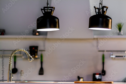 Pair of black hanging lamps above a sink in a modern white kitchen