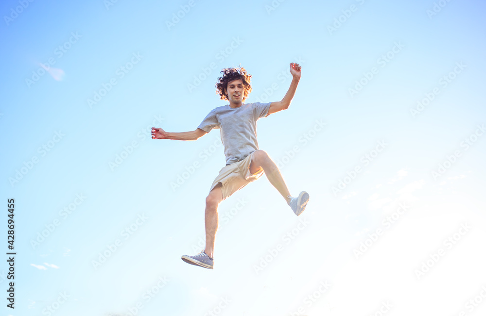 Young man jumping and celebrating with his arms raised and the blue sky in the background. Man jumping for joy and feeling happy and free. Success and happiness concept. Young man jumping and celebrating with his arms raised and the blue sky in the background. Man jumping for joy and feeling happy and free. Success and happiness concept.