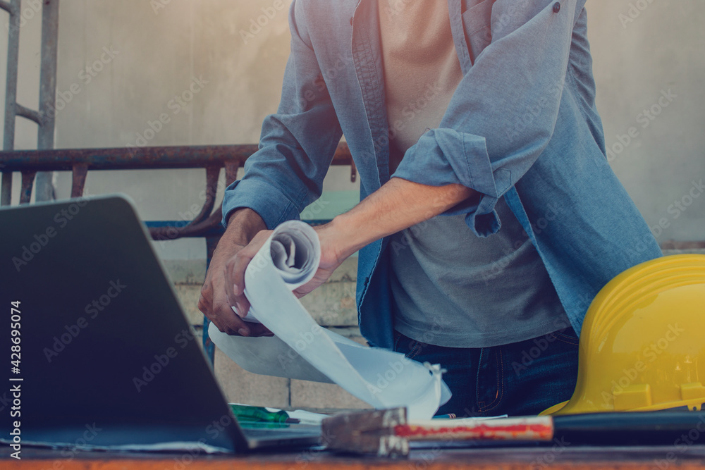Fototapeta premium Engineer holding blueprint working on site construction