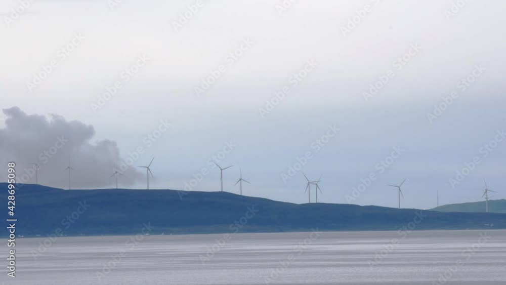 Rotating wind turbines on hills along the coastline. Renewable energy production