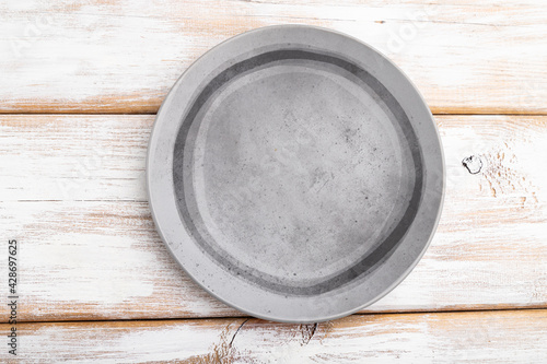 Empty gray ceramic plate on white wooden background. Top view.