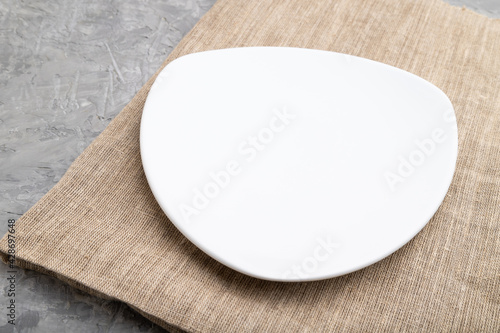 Empty white plate on gray concrete background. Side view.