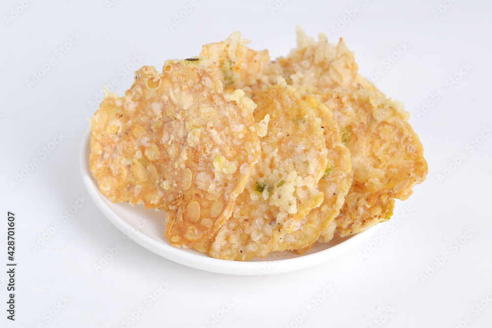 Keripik tempe , tempeh crackers in a plate. Indonesian traditional snack. White background Keripik tempe , tempeh crackers in a plate. Indonesian traditional snack. White background