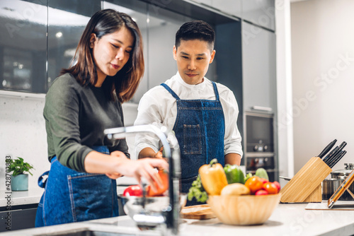 Young asian family couple having fun cooking together with fresh vegetable salad on table.Happy couple prepare the yummy eating lunch in kitchen