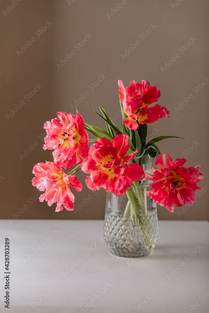 Glass vase with bouquet of beautiful tulips on pastel wall background. Glass vase with bouquet of beautiful tulips on pastel wall background.